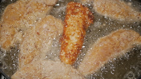 Crumbed-breast-chicken-tenderloins-being-placed-in-peanut-oil-in-a-pan