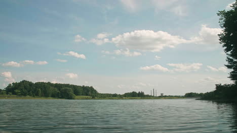 Coal-power-plant-in-distance-from-peaceful-lake-view,-Pan-Left