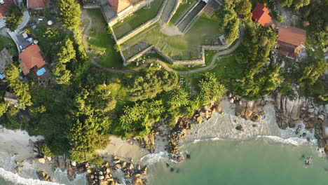 Sunset-drone-aerial-top-view-fortress,-heavenly-brazilian-rocky-coast-beach,-Sao-Jose-Da-Ponta-Grossa,-Jurere-Internacional,-Florianopolis,-Santa-Catarina,-Brazil