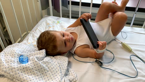Kleiner-Junge-Im-Krankenhausbett,-Der-Filme-Auf-Dem-Smartphone-Anschaut