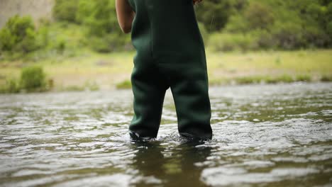 Slow-Motion-Shot-of-a-male-fisherman-wearing-waders-while-Fly-Fishing