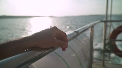 Close-Up-on-a-hand-on-a-rail-of-a-boat-sailing-in-the-ocean-waters