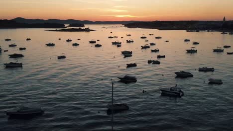 Drohnen-Dolly-Aufnahme-Der-Küste-Mit-Booten-Im-Wasser-Und-Sonnenuntergang-Im-Hintergrund