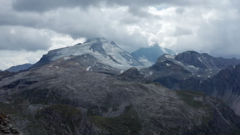 Drone-mountain-view-around-Tignes,-flying-over-rocks-with-La-Grande-Motte-glacier-on-the-back