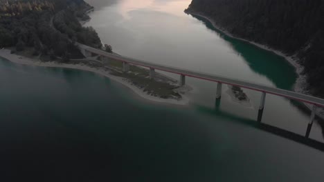 Eine-Professionell-Wirkende-Luftaufnahme-Der-österreichischen-Alpen-Bei-Sonnenuntergang,-Die-Den-Blick-Auf-Eine-Brücke-Freigibt