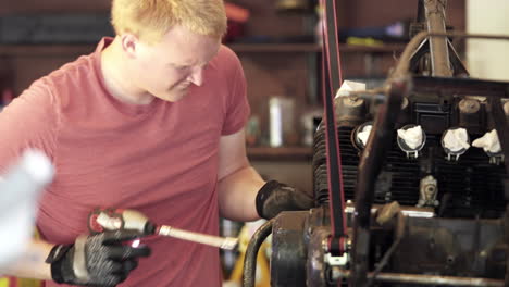 Medium-Close-Up-of-Young-Blonde-Man-Using-Power-Tools-During-Motorcycle-Teardown