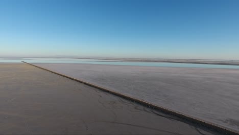 A-drone-shot-flying-over-the-Bonneville-Salt-Flats-shows-the-Salt-Flats-causeway-and-distant-highway
