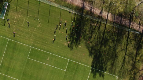 Spinning-aerial-rise-over-soccer-training-grounds-with-active-players