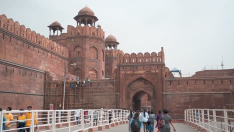 Tourist-walking-in-from-the-main-entrance-to-ancient-old-historial-Red-Fort-Delhi-India-asia-front-view