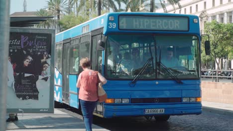 Spanish-woman-runs-up-to-bus,-gets-on,-bus-drives-away,-Slow-Motion