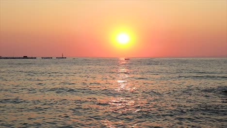 Wunderschöner-Farbenfroher-Sonnenuntergang-Mit-Kleinen-Booten,-Die-Am-Horizont-Schwimmen