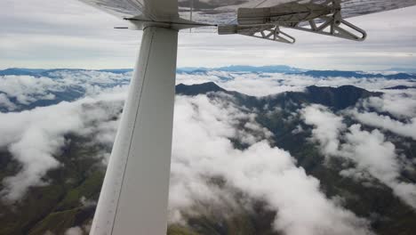 View-from-small-airplane-flying-over-clouds-and-mountain-range