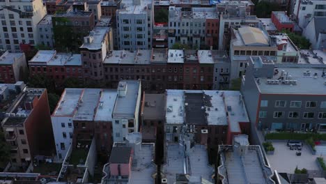 Aerial-footage-slights-sideways-across-brownstone-rooftops-of-Harlem,-NYC,-at-golden-hour-sunrise