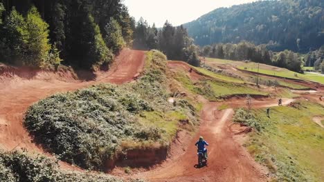 Drone-shot-of-motocross-riders-on-motorbikes-on-dirt-park-track-jumping-and-having-fun