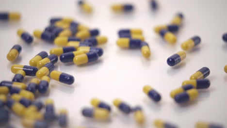 Makro-Aus-Blauen-Und-Gelben-Pillen,-Die-Auf-Weißen-Hintergrund-Gefallen-Sind