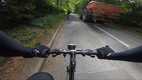 POV-View-Cycling-On-Road-Being-Overtaken-By-Large-Tractor-And-White-Car