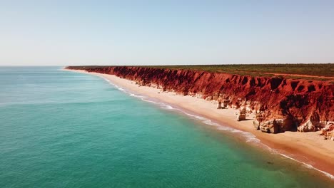 Drone-flying-adjacent-to-spectacular-red-ocean-side-cliffs-and-blue-water-of-Western-Australia