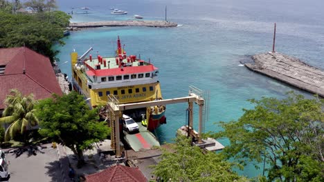 Port-Roro-with-Nusa-Jaya-Abadi-vehicle-ferry-offloading-motorcycles-and-vehicles-originating-in-Bali,-Aerial-dolly-left-reveal-shot