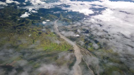 Flying-over-rugged-Papua-New-Guinea-mountains-and-river-above-clouds