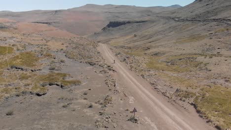 aerial-shot-following-a-mountain-biker-climbing-up-a-pass-on-a-gravel-road