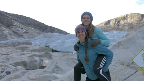 Two-Girls-Pose-for-a-Fun-Photo-by-a-Glacier-in-Norway,-Slow-Motion