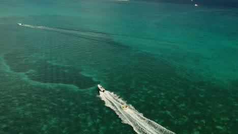 Luftaufnahme-Eines-Sportbootes,-Das-Mit-Menschen-Darauf-Einen-Großen-See-Zieht-Und-In-Atemberaubenden-Gewässern-Segelt