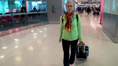 Woman-pulls-carry-on-luggage-through-an-airport-with-a-courtesy-transport-pulling-up-to-her