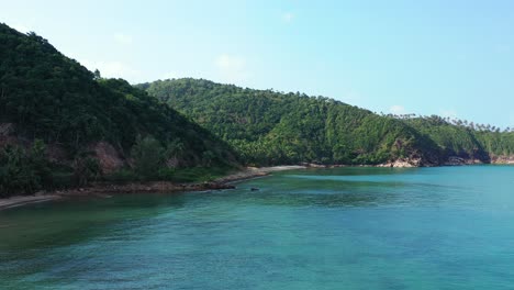 Hermosa-Costa-Aislada-De-Isla-Tropical-Con-Laderas-Rocosas-Que-Bajan-Al-Fondo-Del-Mar-Bajo-Aguas-Tranquilas-Y-Claras-De-La-Laguna-Azul-En-Koh-Pha-Ngan,-Tailandia