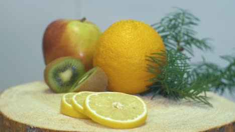 Nahaufnahme-Einer-Kamera,-Die-Auf-Die-Früchte,-Orange,-Apfel,-Kiwi-Und-Zitrone-Auf-Einem-Holzschreibtisch-Zoomt-Und-Den-Fokus-Von-Zitrone-Zu-Kiwi-Und-Apfel-Wechselt