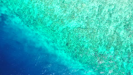 Colorful-sea-texture-with-deep-blue-water-and-shallow-turquoise-lagoon-with-coral-reefs-and-white-sand-in-Dominican-Republic