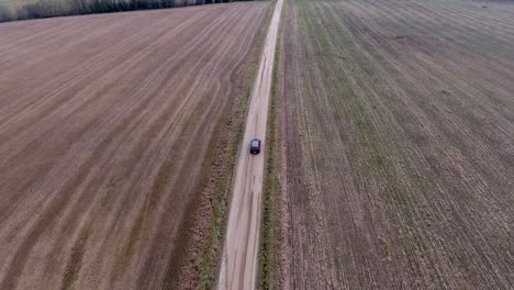 Car-drivin-in-middle-of-the-empty-field,-aerial-shot