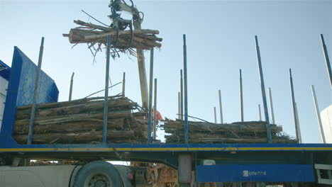 Crane-operator-deftly-stacks-lumber-on-back-of-truck,-low-angle