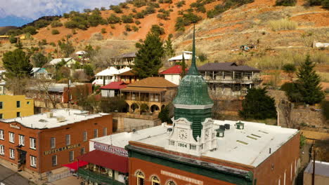 The-Iconic-Pythian-Castle-In-Bisbee,-Arizona-With-Its-Recognizable-Green-Clock-Tower-And-Spire---Drone-Shot