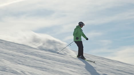 Man-in-green-sport-outfit-skiing-on-the-slope