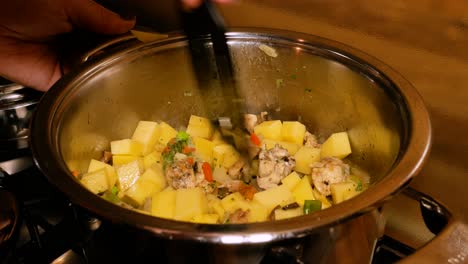 Female-hands-are-mixing-steaming-hot-stew-in-steel-pot-on-oven