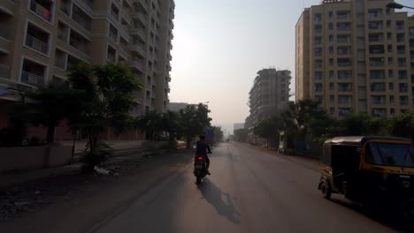 Junge,-Der-Mit-Dem-Fahrrad-Auf-Einer-Leeren-Straße-In-Der-Indischen-Mira-Road-In-Mumbai-Fährt-Und-Große-Gebäude-Am-Morgen-Des-Sonnenaufgangs-Entwickelt