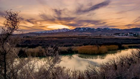 Day-to-night-mountain-sunset-time-lapse-with-the-sky-reflecting-off-the-surface-of-the-river---zoom-out-to-reveal-a-wide-angle-panorama-view