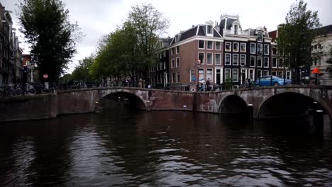 Time-lapse-of-tourist-canal-pleasure-boats-turning-through-bridges-in-Amsterdam,-Holland,-Netherlands,-Europe