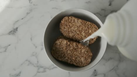 Slow-motion-Milk-poured-onto-weetabix-biscuit-cereal-white-marble