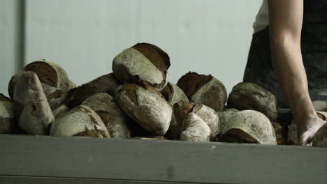 Baker-Arranging-The-Stack-Of-Sourdough-Bread-In-A-Bakery