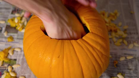 Pumpkin-Carving-Inside-of-Jack-O'-Lantern-by-Spoon-and-Male-Hands-with-seeds-insides:-Ripe-vivid-orange-pumpkin-getting-carved-for-Halloween-decoration