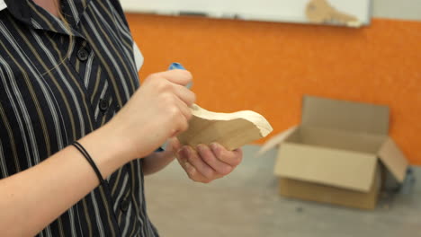 Student-Sanding-A-Piece-Of-Timber-With-Sandpaper,-CLOSE-UP