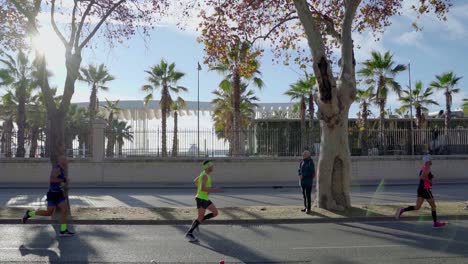 Runners-racing-at-Malaga's-marathon-in-slow-motion-with-sun-behind,-Spain