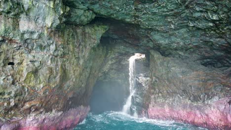 4K-Hawaii-Kauai-Boating-on-ocean-Medium-shot-drifting-away-from-waterfall-in-cave