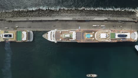 Top-down-cinematic-pan-left-of-aerial-view-of-cruise-ships-docked-in-port-in-the-city-of-Ponta-Delgada,-Azores