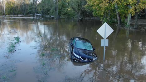 Blue-Honda-Civic-sedan-stranded-in-flooded-river,-aerial-point-of-interest