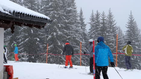 Skiers-preparing-to-ski-during-snowfall.-Static,-slomo