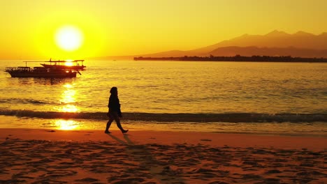 Mujer-Caminando-Por-La-Playa-Al-Atardecer-En-La-Polinesia-Francesa,-Barcos-Flotando-En-El-Mar-En-Calma,-Sol-Y-Horizonte-De-Color-Dorado