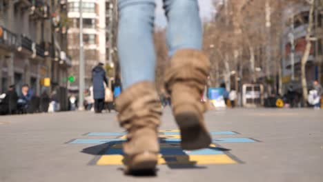 Woman-Jumping-and-Playing-Hopscotch-on-Pedestrian-Street,-Low-angle,-Slow-Motion