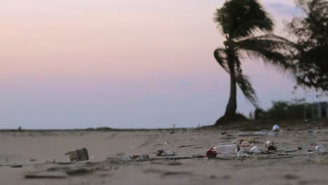 Dirty-tropical-beach-with-trash,-litter-and-plastic-waste-on-the-sand-washed-out-by-the-ocean-to-the-shore